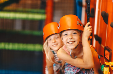 Two happy school girls in sport helmets at climbing class. Indoor bouldering class for school...
