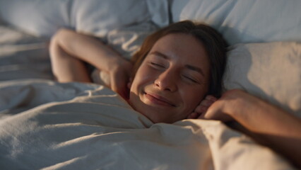 Happy woman stretching bed in sunlight closeup. Carefree smiling girl waking up