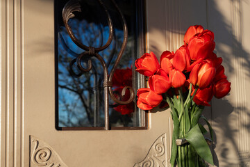 bouquet of fresh red tulips on the front door handle. Surprise, pleasant unexpected gift, sign of...