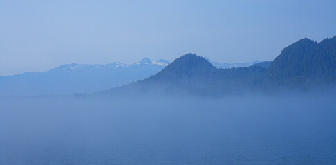 View of snow capped mountains appearing above a sea of clouds in the Inside Passage of Southeastern...