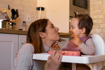 Mother and daughter in the kitchen, eating spaghetti together