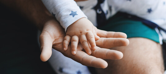 Concept banner lifestyle parenting fatherhood moment. Closeup hand of newborn baby boy son lies on top of his father