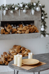 Cozy indoor setting with candles on a table, surrounded by wrapped gifts and firewood. The white tiled floor contrasts with the dark table.