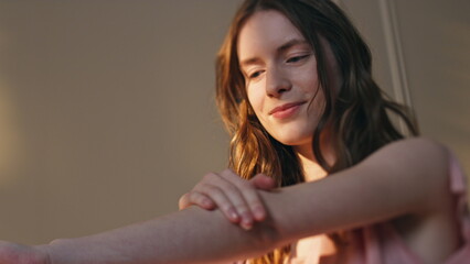 Closeup girl applying lotion on smooth skin in sunlight. Serene woman enjoying