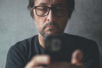 Man using cellphone at home, closeup shot of unkempt male with smartphone in hands - obrazy, fototapety, plakaty