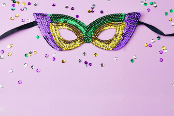 A festive colorful carnival mask for the Mardi Gras festival on a lilac background with sparkling...