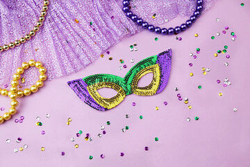 Decorations for the Mardi festival, carnival mask, beads, confetti on a lilac background. Festive...