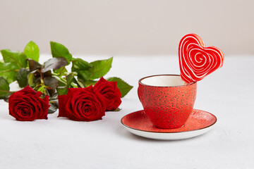 A red cup with a heart-shaped lollipop, a bouquet of red roses. A postcard for Valentine's Day,...