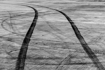 Tire track mark on asphalt tarmac road race track texture and background, Abstract background black tire tracks skid on asphalt road in racing circuit, Tire mark skid mark on asphalt road. © Darunrat