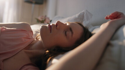 Morning girl open eyes in sunlight closeup. Peaceful smiling woman waking up