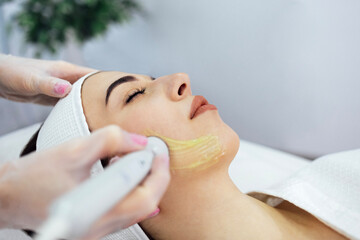 Fototapeta na wymiar Closeup of face of beautiful relaxing girl undergoing hardware cosmetology procedure in spa.