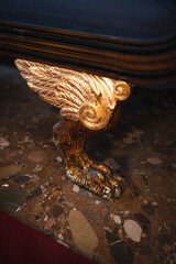 Furniture details. Carved wooden lions paw with gold wings.