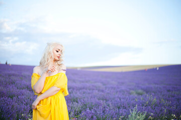 beautiful blonde in a yellow dress walks in a lavender field