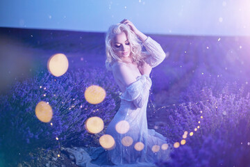 a young girl in a transparent dress sits in a lavender field. Provence. evening photo