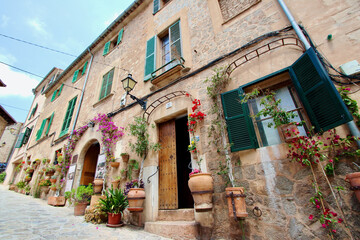 Fototapeta na wymiar View of idyllic Valldemosa village old houses decorated with seasonal plants and flowers, Mallorca, Balearic Islands, Spain (no property release added as shop names and property have been deleted)