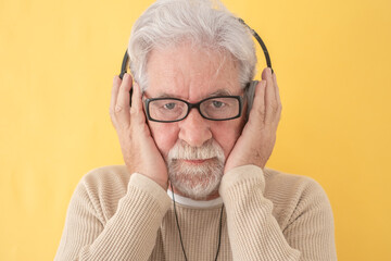 Closeup portrait of concentrated senior bearded man holding headphones on head listening music