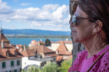 Side view of mature senior woman in vacation looking at lake landscape enjoying travel in a sunny...