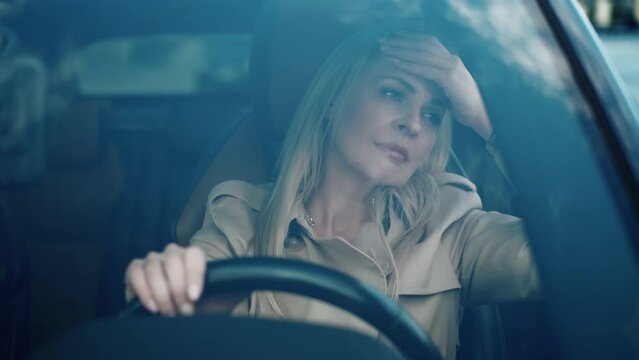 The stressed girl driver sitting inside car. Sad business woman is having headache. Driving car in traffic jam on rush hour. Exhausted overworked driver. Disappointment and migraine concept
