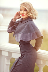 stylish girl in pin-up style with a fashionable hairstyle in an autumn coat against the backdrop of the city.