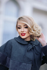Fototapeta premium stylish girl in pin-up style with a fashionable hairstyle in an autumn coat against the backdrop of the city.
