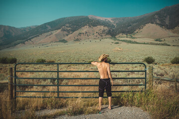 Man wearing shorts and cowboy hat, shirtless and back facing to camera. 