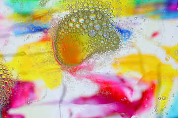 Macro shot of water-oil emulsion over colored background