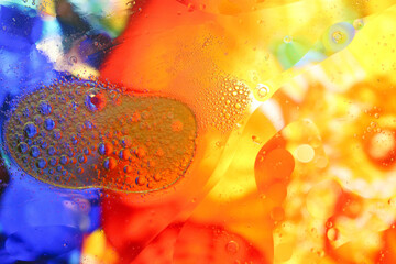 Macro shot of water-oil emulsion over colored background