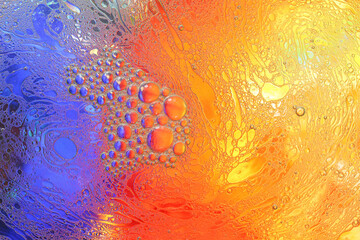 Macro shot of water-oil emulsion over colored background