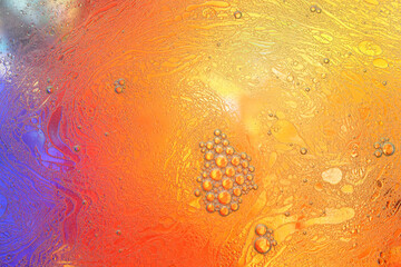 Macro shot of water-oil emulsion over colored background