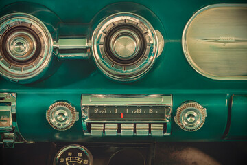 Retro styled image of an old car radio inside a green classic American car - obrazy, fototapety, plakaty