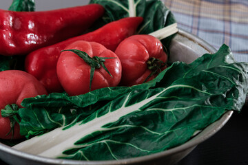 fresh chard leaves green ready to cook or salad with tomatoes and red pepper on dark background