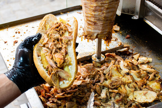 Close-up of a male hand holding a delicious chicken shawarma sandwich in bread.