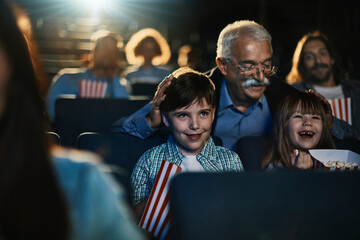 Happy grandfather watching a movie with grandchildren at cinema