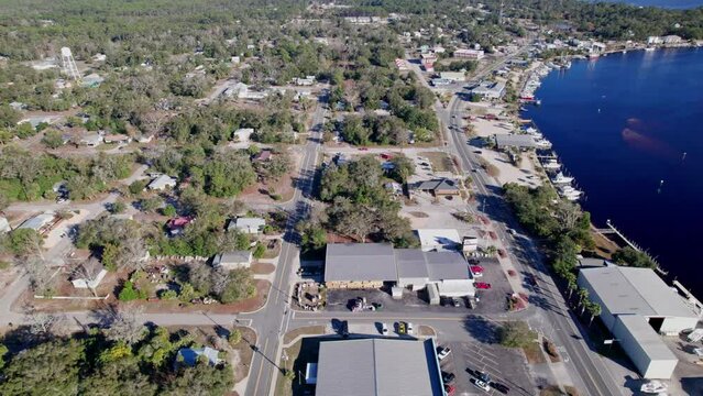 Middle class neighborhood homes from aerial drone view birds-eye-view from above looking down on buildings, streets, neighbors, and cars in small town by Gulf of Mexico ocean coastline