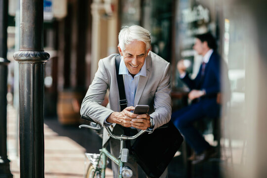 Senior businessman using smartphone during bike commute in city
