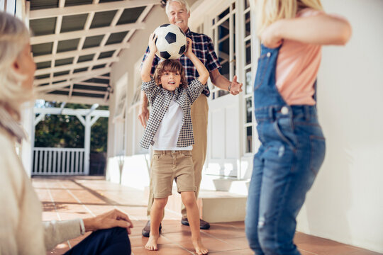 Fototapeta Multi-generational family playing soccer together on the porch