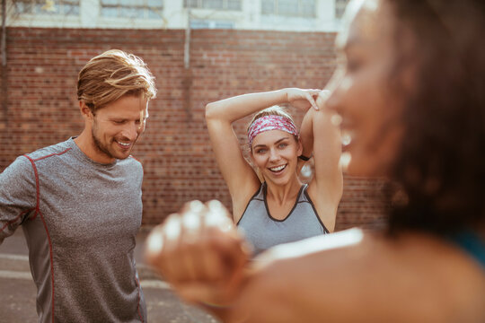 Group of diverse runners stretching before city jog
