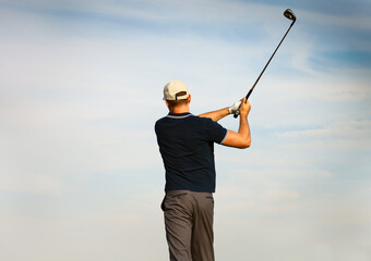 Athletic young man playing golf, golfer hitting fairway shot
