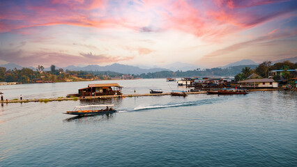 Fototapeta na wymiar Kanchanaburi Province,Thailand - 13th December 2023: Floating house and long tail boat in river with sunset view at Sangkhlaburi, Kanchanaburi Province,Thailand.