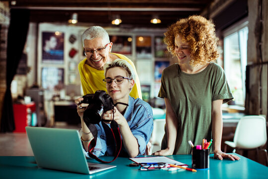 Senior woman teaching photography to young adults in a creative workspace