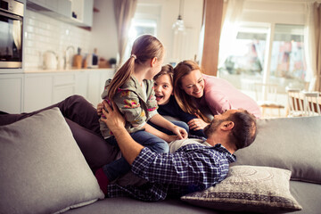 Young family playing having fun on the couch at home
