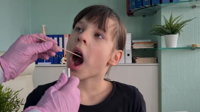 Female pediatrician using swab to take sample from a patient throat