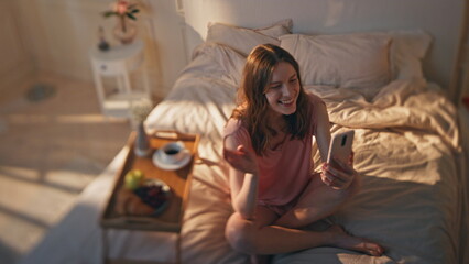 Joyful woman videocalling online at home bedroom. Smiling teenager waving mobile