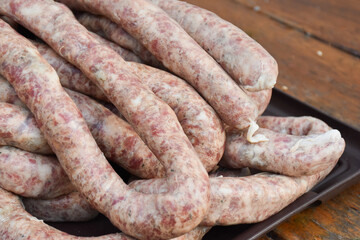Raw long sausages on a tray close up. Fresh traditional homemade sausages texture