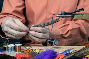 Close up on young man's hands tying a fly for fishing