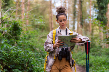 The curly-haired beauty takes a break on the forest trail, checking her map to navigate the serene autumn surroundings.
