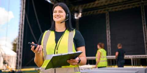 Portrait Of Female Production Worker Setting Up Outdoor Stage For Music Festival Or Concert - obrazy, fototapety, plakaty