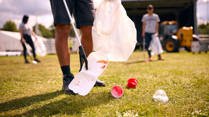 Close Up Of Volunteers Picking Up Litter After Outdoor Event Like Concert Or Music Festival