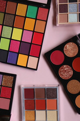 Various colorful eyeshadow palettes on bright pink background. Flat lay.
