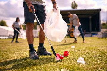 Close Up Of Volunteers Picking Up Litter After Outdoor Event Like Concert Or Music Festival - Powered by Adobe